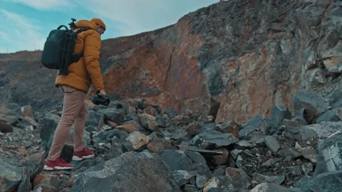 Bearded man in a hat with a backpack comes down from the mountains Stock Footage 145409794