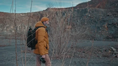 Bearded man in a hat with a backpack comes down from the mountains Stock Footage 146226642