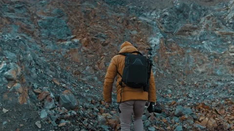 Bearded man in a hat with a backpack comes down from the mountains Stock Footage 149671911