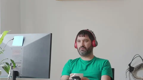Bearded man having coffee in front of computer with headphones in modern office Stock Footage 147547830