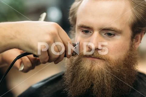 Bearded man having a haircut with a hair clippers Stock Photos