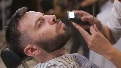 Bearded man having his beard cut by hairdresser at the barbershop Stock Footage 93709524