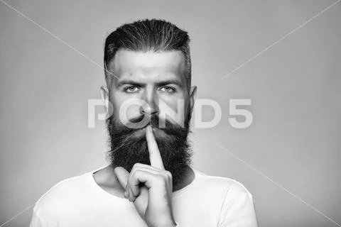Bearded man with hush gesture Stock Photos