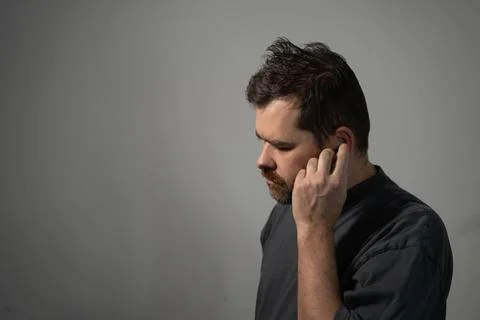 Bearded man inserting wireless earbud in ear Stock Photos