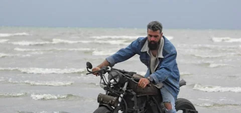 Bearded man in jeans on his old cafe racer motorcycle near sea Stock Footage 140624656