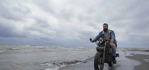 Bearded man in jeans on his old cafe racer motorcycle near sea Stock Footage 140624845