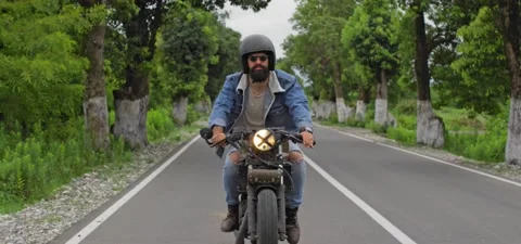 Bearded man in jeans rides old cafe racer motorcycle on country road Stock Footage 140624161