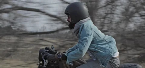 Bearded man in jeans rides old cafe racer motorcycle on country road Stock Footage 140653199