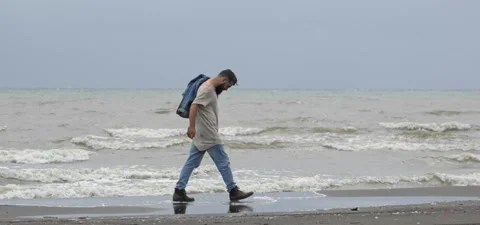 Bearded man in jeans on sandy beach near sea in slow motion Stock Footage 140624626