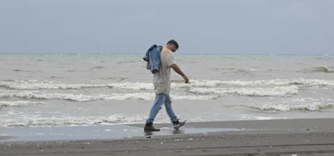 Bearded man in jeans on sandy beach near sea in slow motion Stock Footage 140624634