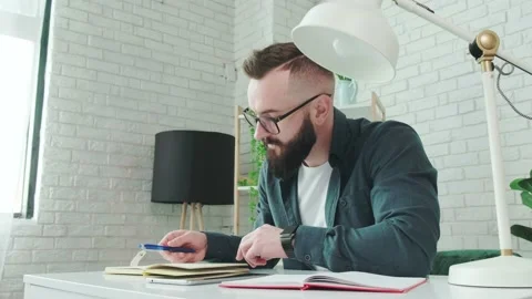 Bearded man learn online courses using a tablet and write notice in his notebook Stock Footage 155760120