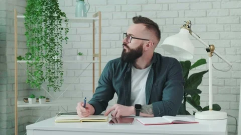 Bearded man learn online courses using a tablet and write notice in his notebook Stock Footage 156327654