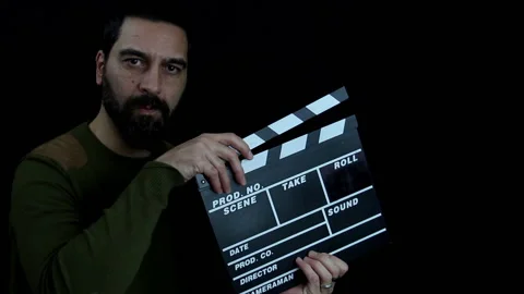 Bearded man looks into the camera and beats the clapperboard, film production Stock Footage 143486273