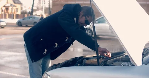 Bearded man looks for errors in the car at market parking Stock Footage 86978515