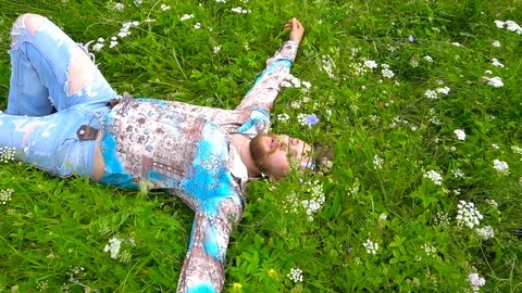 Bearded man is lying in a green flower field Stock Footage 79603551