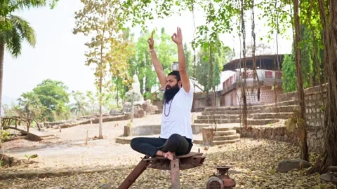 Bearded man meditates in nature balancing pot on head Stock Footage 303127953