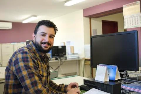 Bearded man in office at computer, working and smiling Stock-Fotos