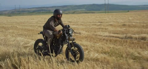 Bearded man on old cafe racer motorcycle in wheat field Stock Footage 140622099