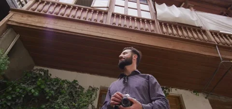 Bearded man with old camera enjoys old city view Stock Footage 140265066