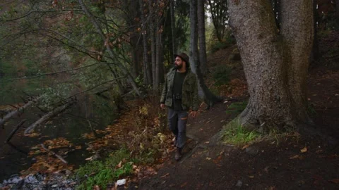 Bearded man with old camera walks in autumn forest near a lake Stock Footage 138123306