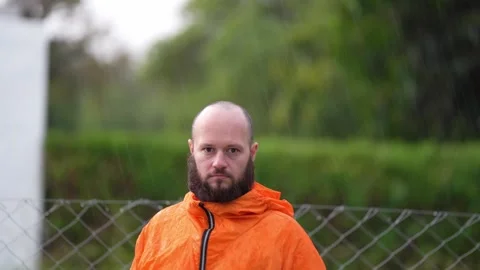 Bearded man in orange jacket looking at the camera in nature 스톡 동영상 295970150