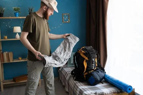 Bearded man packing backpack for camping trip Stock Photos