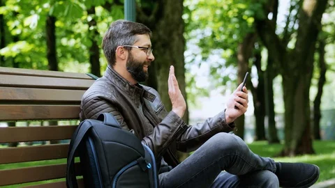Bearded man in the park helps his wife in shopping via video link Stock Footage 107987233