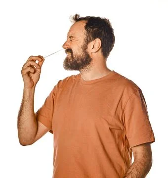 Bearded man performing antigen test with unpleasant expression. on white isol Stock Photos