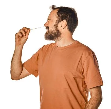 Bearded man performing antigen test with unpleasant expression. on white isol Stock Photos