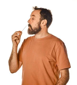 Bearded man performing antigen test with unpleasant expression. on white isol Stock Photos