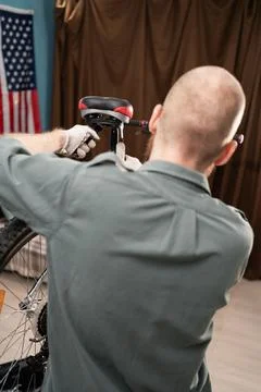 Bearded man is performing maintenance on his bike at home. fixing bicycle Stock Photos