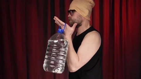 Bearded man performs Bicep curls using a large bottle of water as a weight. Stock Footage 131584125