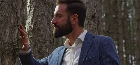 Bearded man in pine forest, explores tree Video stock 140268172