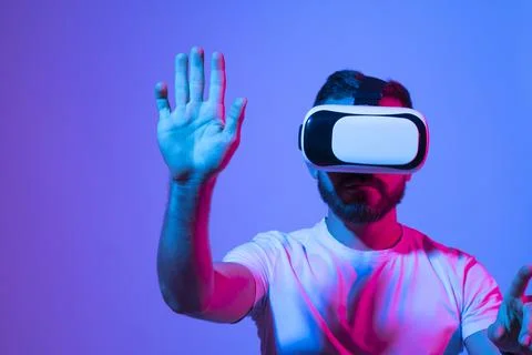 Bearded man playing VR video game in metaverse with virtual reality goggles and Stock Photos