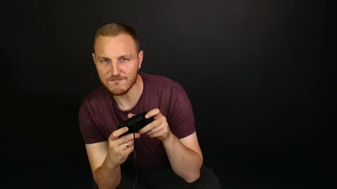 Bearded man plays console black background, completely absorbed in the game Video stock 115508663