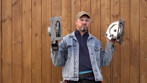 Bearded man poses with electric saws 4K Stock Footage 291268396