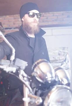 Bearded man posing with his shiny stylish chopper. Stock Photos