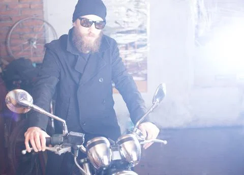Bearded man posing with his shiny stylish chopper. Stock Photos