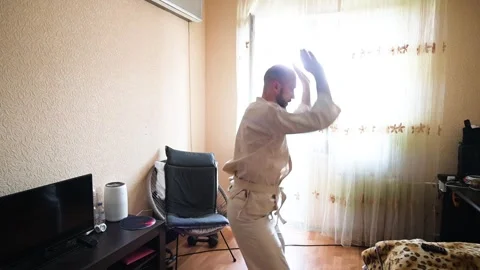 A bearded man practicing martial arts forms and movements inside a home room Stock Footage 345496656