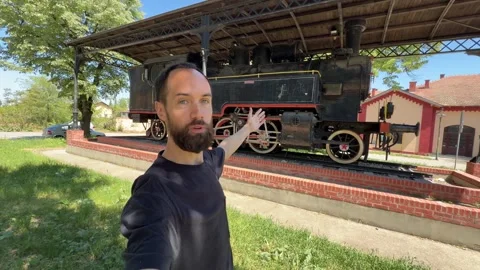 Bearded Man Presenting Historic Steam Locomotive Monument in Kikinda Vídeos de archivo 334045820