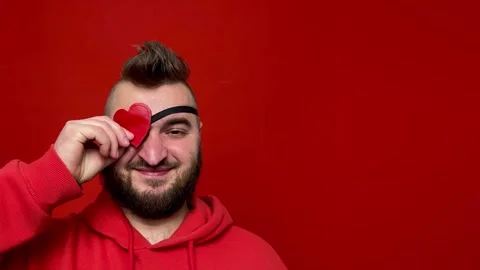 Bearded man puts on heart-shaped occluder on red background Stock Footage 272719588