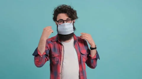 Bearded man puts a mask on his face from air pollution and coronavirus. Stock Footage 139692228