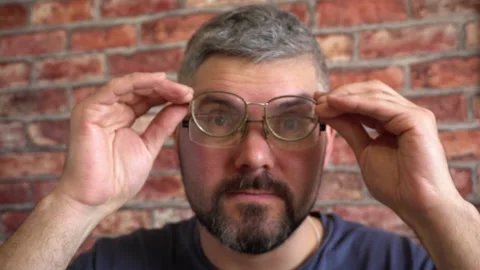 Bearded man puts on second glasses on his face 4K Video stock 150287319