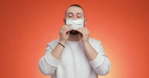 Bearded man is putting on mask and showing thumb up gesture on red background. Stock Footage 149072801
