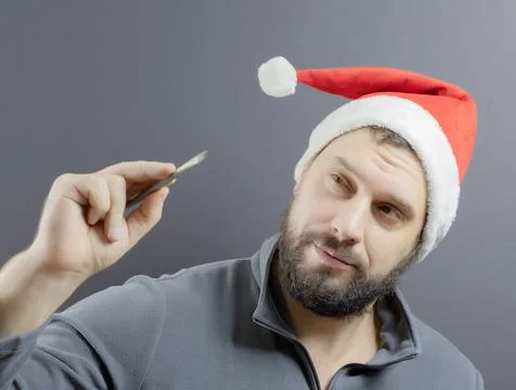 A bearded man in a red santa hat holds an art brush in his hand. Santa artist Stock Photos
