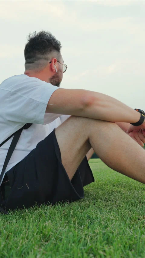 Bearded Man Relaxing on Grass with Wireless Earbuds in Washington DC Park. Vídeos de archivo 342959750