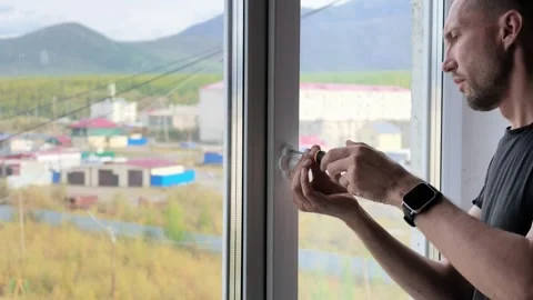 Bearded man removes window handle with screwdriver revealing three holes in Stock Footage 345521262