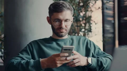 Bearded Man Resting In Cafe In Daytime, Using Smartphone, Surfing Internet And Video stock 343669359