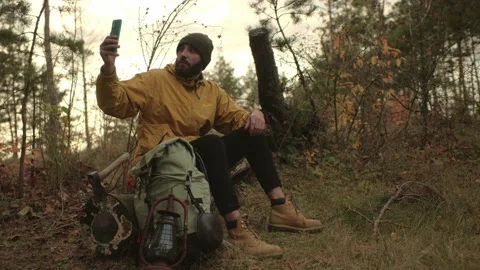 A bearded man rests on a fallen tree in the middle of the forest. Stock Footage 220189175