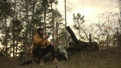 A bearded man rests on a fallen tree in the middle of the forest. Stock Footage 220189185